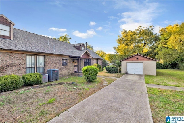 exterior space featuring an outbuilding, a garage, a lawn, and central AC unit