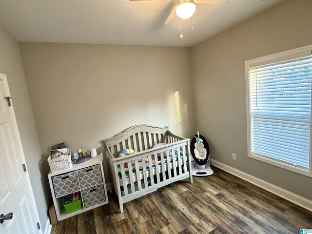 bedroom with baseboards, a ceiling fan, wood finished floors, and a nursery area