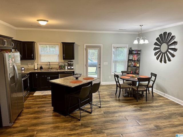 kitchen featuring light stone counters, a sink, a wealth of natural light, stainless steel appliances, and a kitchen island
