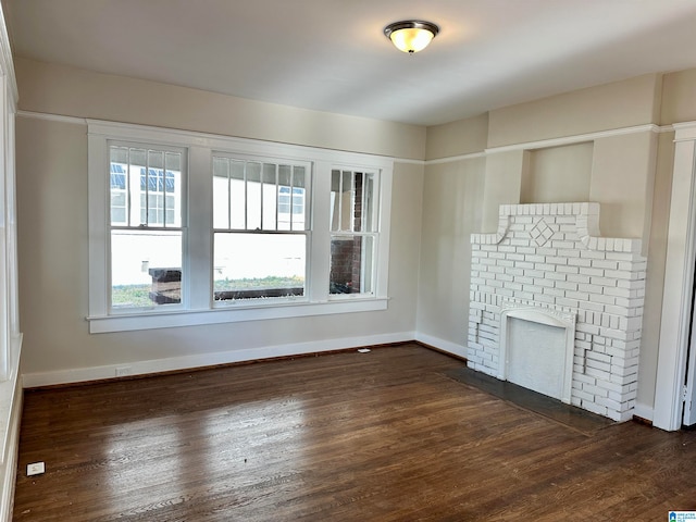 unfurnished living room with dark hardwood / wood-style flooring and a brick fireplace