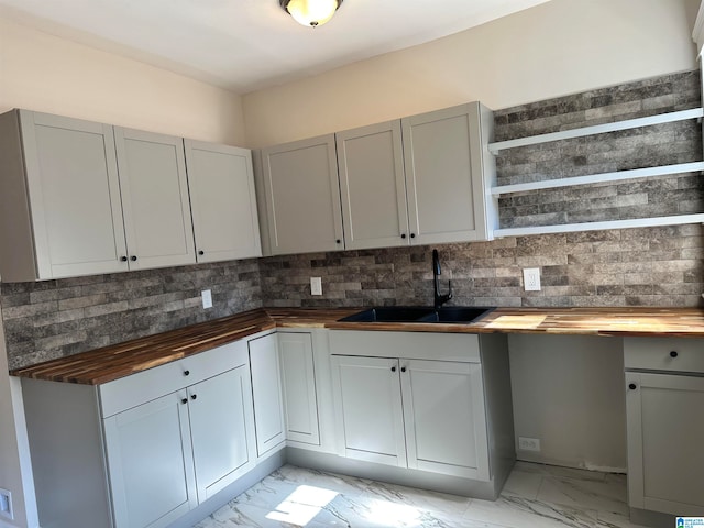 kitchen with decorative backsplash, butcher block countertops, gray cabinetry, and sink