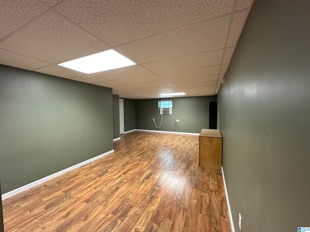 basement featuring a paneled ceiling and hardwood / wood-style flooring