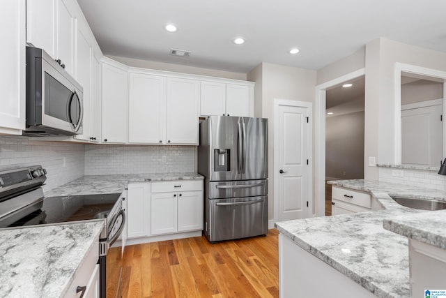 kitchen with light hardwood / wood-style floors, appliances with stainless steel finishes, sink, and white cabinetry