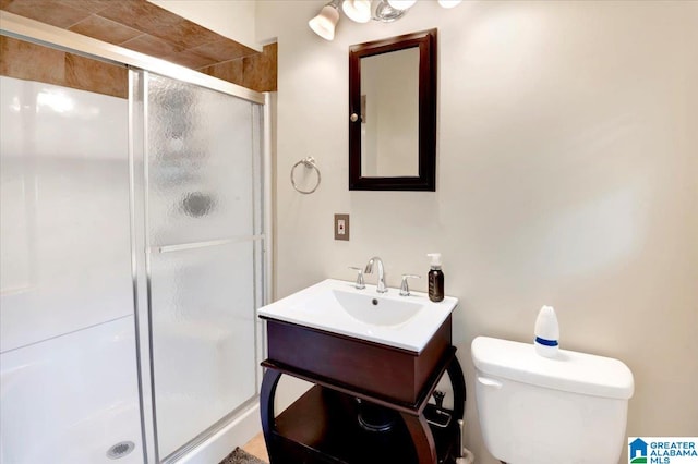 bathroom with vanity, a shower with door, and toilet