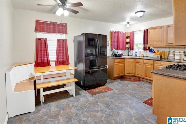 kitchen with ceiling fan, decorative backsplash, sink, black fridge, and a textured ceiling