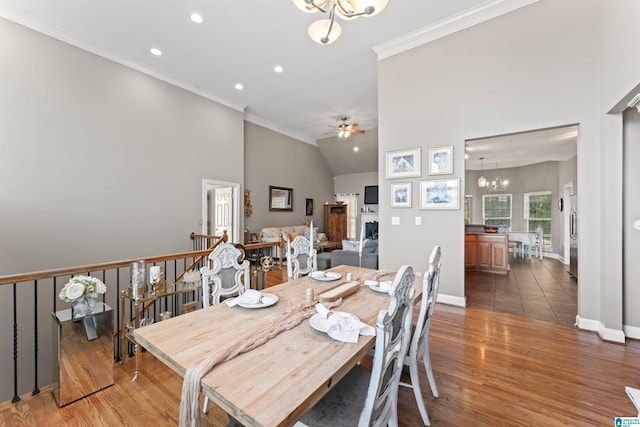 dining area featuring ceiling fan with notable chandelier, high vaulted ceiling, ornamental molding, and dark hardwood / wood-style floors