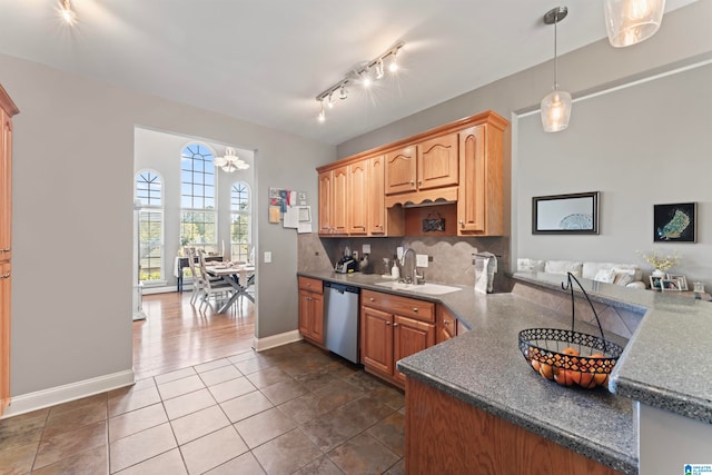 kitchen with decorative backsplash, hanging light fixtures, stainless steel dishwasher, dark tile patterned flooring, and sink