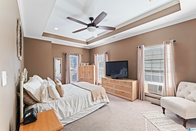 bedroom with ceiling fan, light carpet, ornamental molding, and a tray ceiling