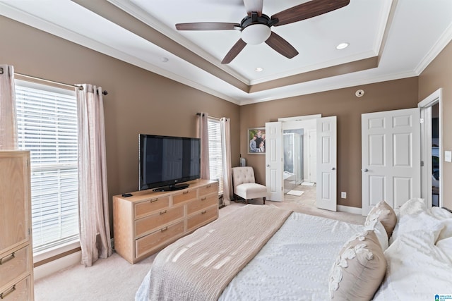 bedroom featuring connected bathroom, ornamental molding, light colored carpet, a raised ceiling, and ceiling fan