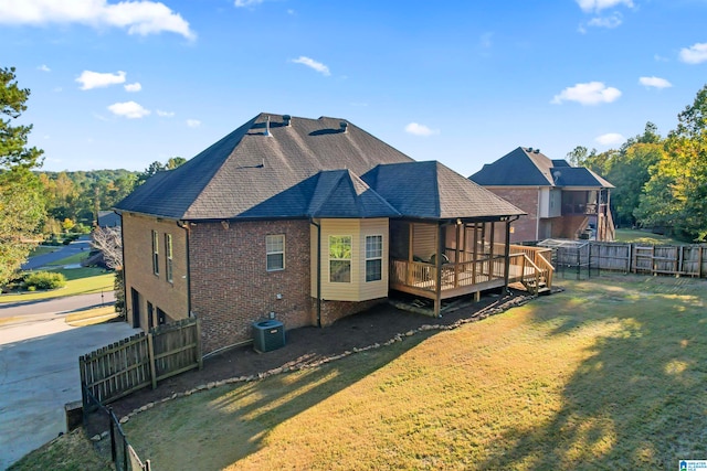 back of property with a wooden deck, a yard, and central AC unit