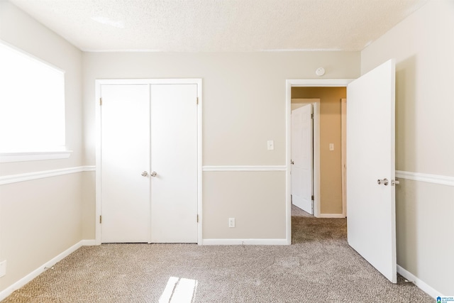 unfurnished bedroom with a closet, a textured ceiling, and light carpet