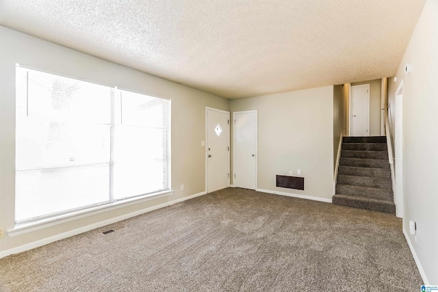 interior space with a textured ceiling and carpet flooring