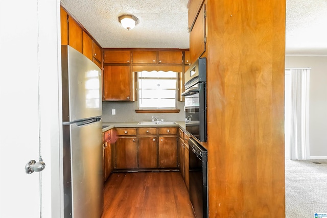 kitchen featuring dark hardwood / wood-style floors, crown molding, black appliances, and sink