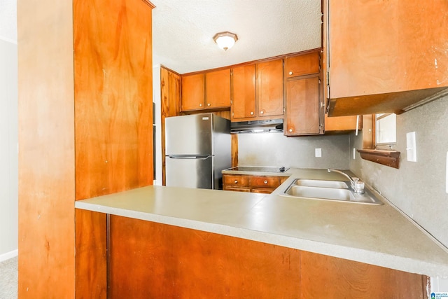 kitchen with stainless steel fridge, sink, kitchen peninsula, black electric stovetop, and a textured ceiling