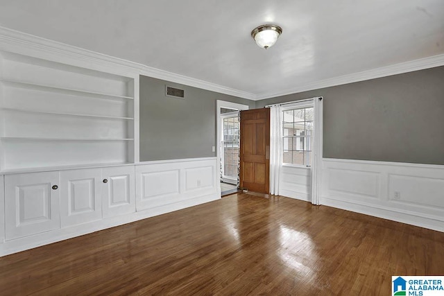 unfurnished room featuring crown molding, dark hardwood / wood-style floors, and built in shelves