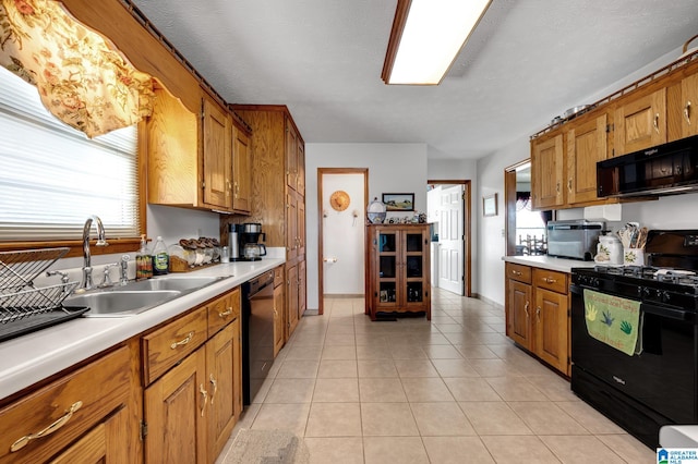 kitchen with light tile patterned flooring, black appliances, sink, and a textured ceiling