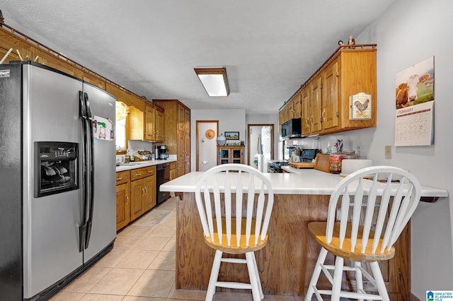 kitchen with light tile patterned floors, kitchen peninsula, a textured ceiling, black appliances, and a kitchen bar