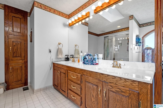 bathroom with tile patterned flooring, a shower with door, vanity, and a textured ceiling