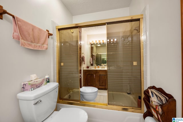 full bathroom featuring bath / shower combo with glass door, vanity, toilet, and a textured ceiling