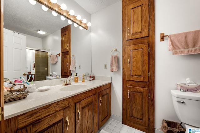 bathroom with an enclosed shower, vanity, toilet, and a textured ceiling