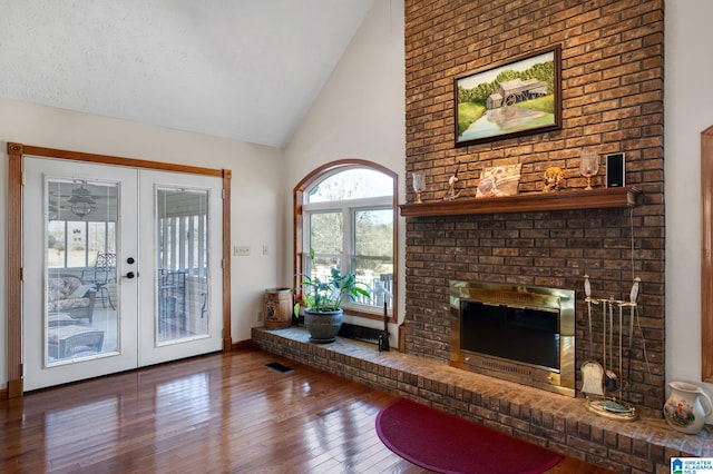 living room featuring french doors, high vaulted ceiling, hardwood / wood-style floors, and a textured ceiling