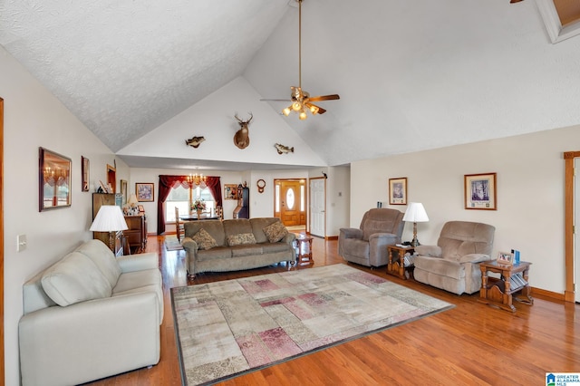 living room with ceiling fan with notable chandelier, high vaulted ceiling, hardwood / wood-style floors, and a textured ceiling