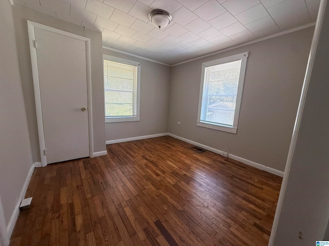 spare room featuring ornamental molding and dark hardwood / wood-style flooring