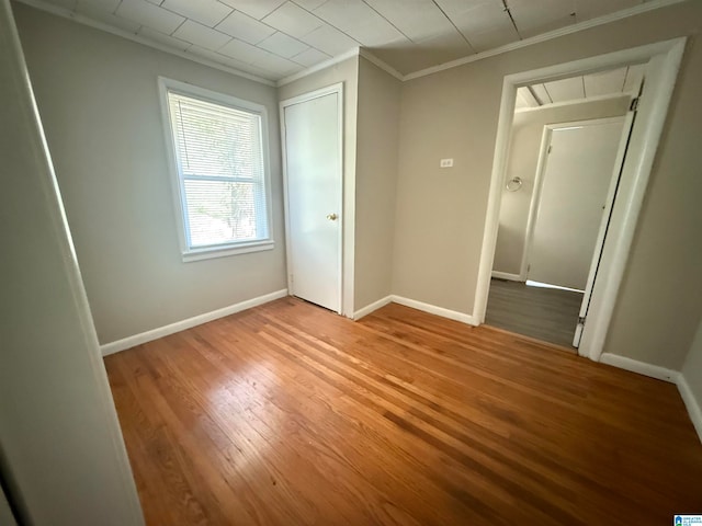 unfurnished bedroom featuring crown molding, a closet, and light hardwood / wood-style floors