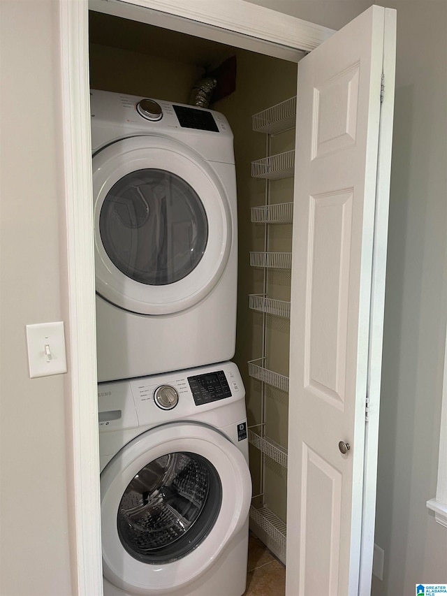 laundry room featuring stacked washer / drying machine and tile patterned flooring