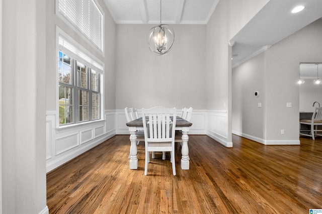 dining space with dark wood-type flooring, a notable chandelier, and ornamental molding