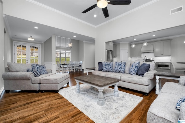 living room with a high ceiling, dark hardwood / wood-style floors, ceiling fan, and crown molding