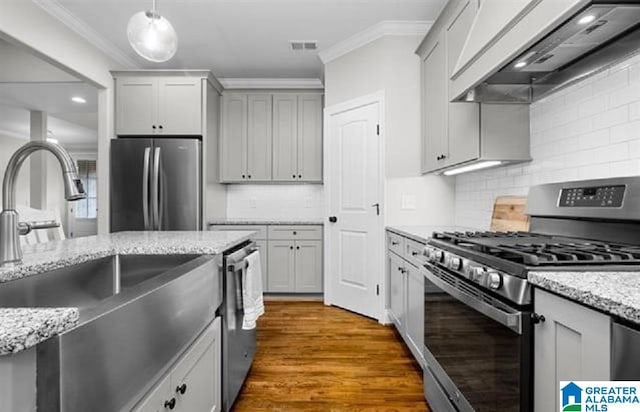 kitchen featuring dark wood-type flooring, pendant lighting, gray cabinets, exhaust hood, and appliances with stainless steel finishes