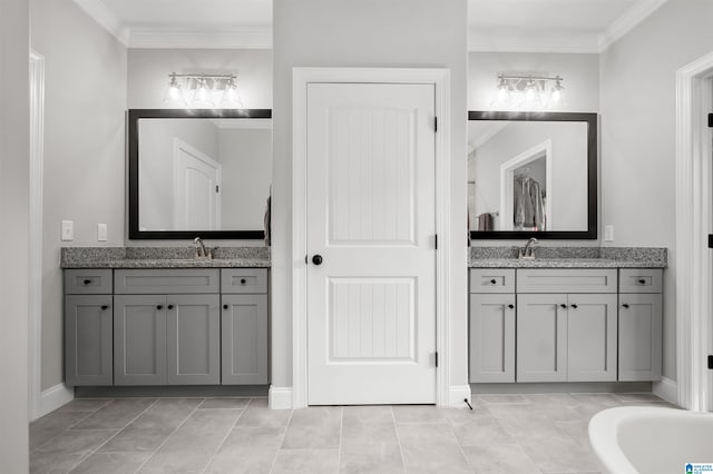 bathroom with tile patterned floors, vanity, a bathtub, and crown molding