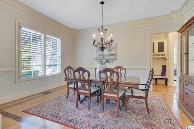 dining space featuring an inviting chandelier, crown molding, and light hardwood / wood-style flooring