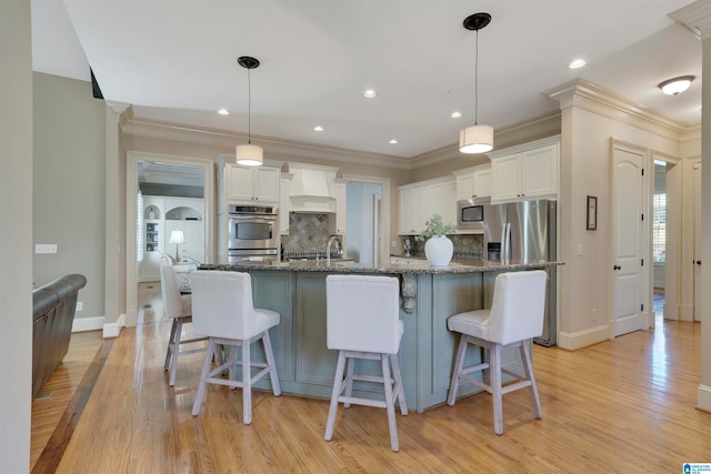 kitchen with light wood-type flooring, dark stone counters, and white cabinetry