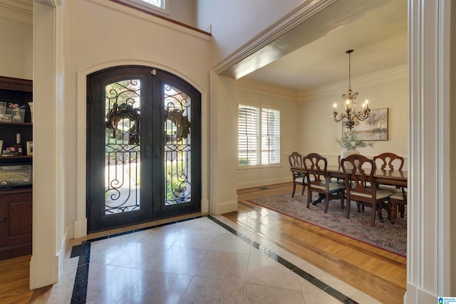 foyer with a notable chandelier, french doors, hardwood / wood-style flooring, and ornamental molding