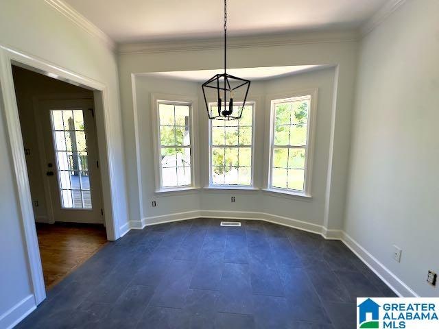 unfurnished dining area featuring dark wood-type flooring, crown molding, a notable chandelier, and a wealth of natural light