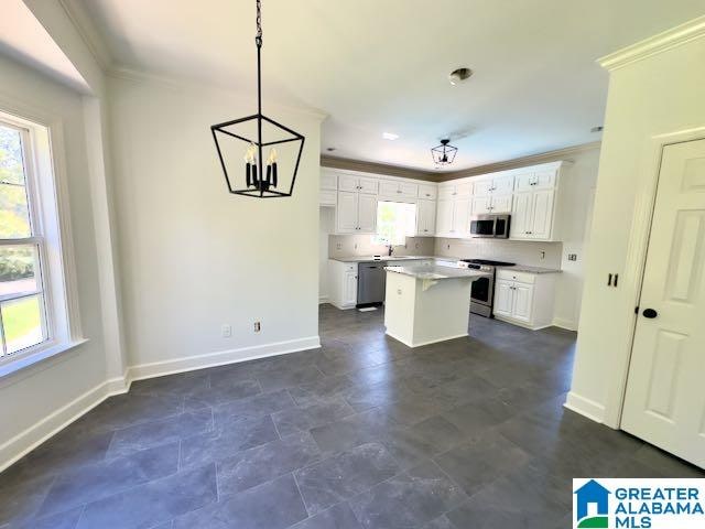 kitchen with a center island, stainless steel appliances, pendant lighting, crown molding, and white cabinetry