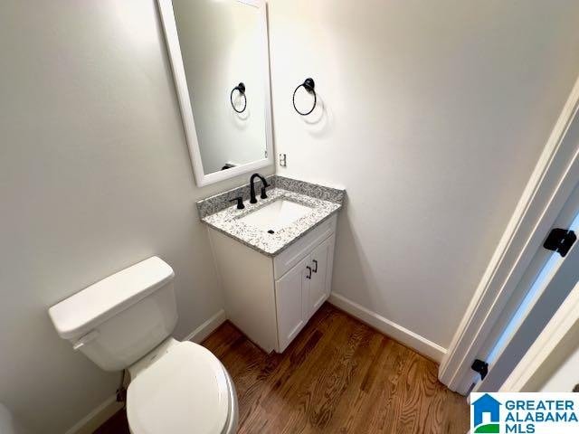 bathroom featuring wood-type flooring, vanity, and toilet