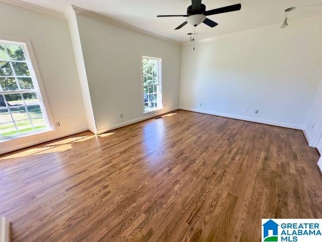 empty room featuring wood-type flooring, plenty of natural light, ornamental molding, and ceiling fan