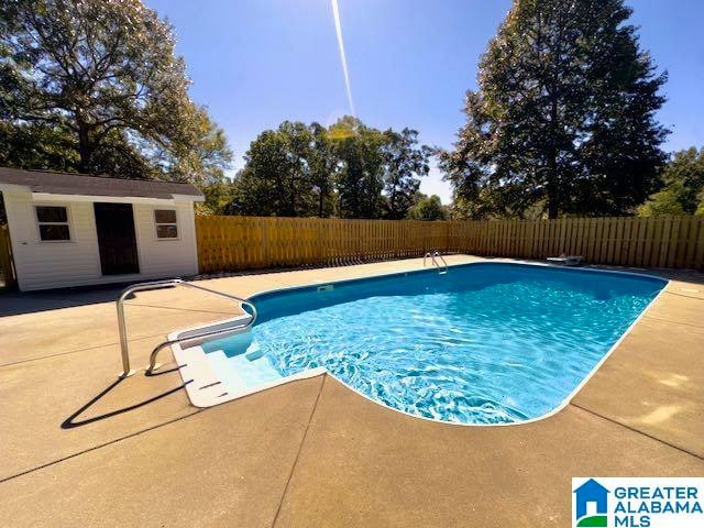 view of swimming pool with an outbuilding and a patio