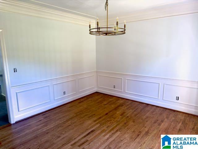 unfurnished dining area with dark hardwood / wood-style floors, crown molding, and a chandelier