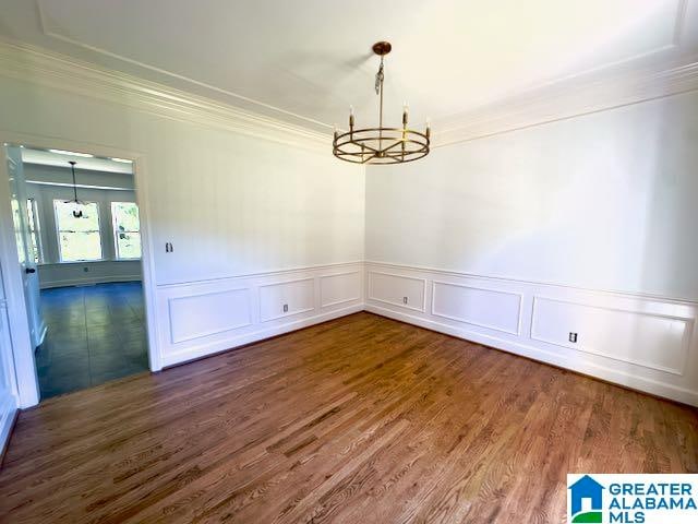 unfurnished dining area with ornamental molding, dark hardwood / wood-style floors, and an inviting chandelier