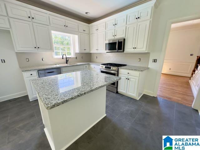 kitchen with a kitchen island, light stone counters, white cabinetry, and stainless steel appliances