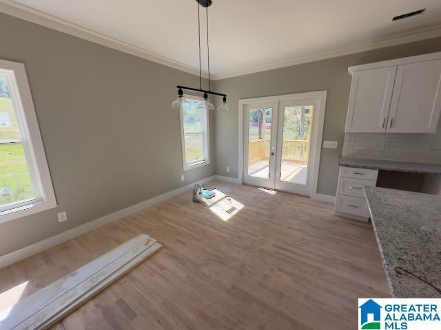 unfurnished dining area featuring crown molding, french doors, and light wood-type flooring