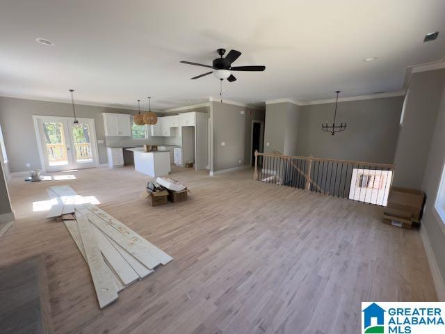 unfurnished living room with crown molding, ceiling fan with notable chandelier, and light hardwood / wood-style floors