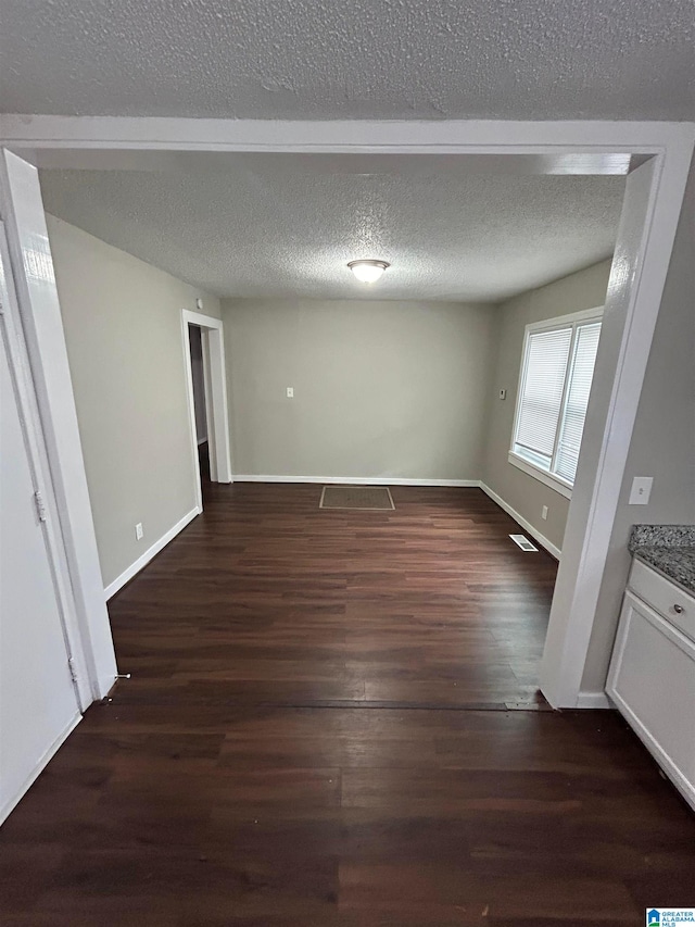 unfurnished room featuring dark wood-type flooring and a textured ceiling