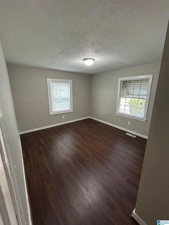 spare room featuring dark hardwood / wood-style floors and a textured ceiling