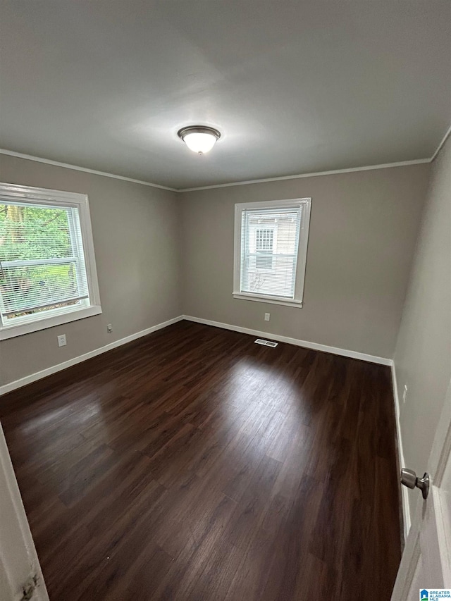 unfurnished room featuring ornamental molding and dark wood-type flooring