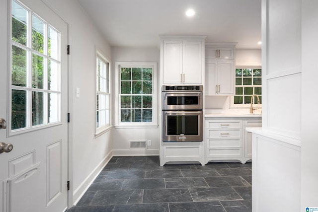 kitchen featuring recessed lighting, light countertops, visible vents, double oven, and white cabinetry